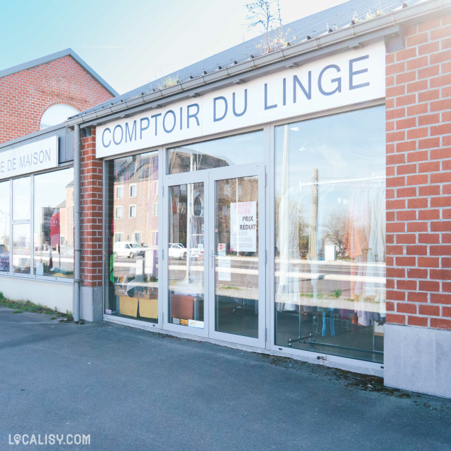 Devanture d’un magasin nommé "Comptoir du Linge", avec une vitrine vitrée et une enseigne blanche à lettres noires.