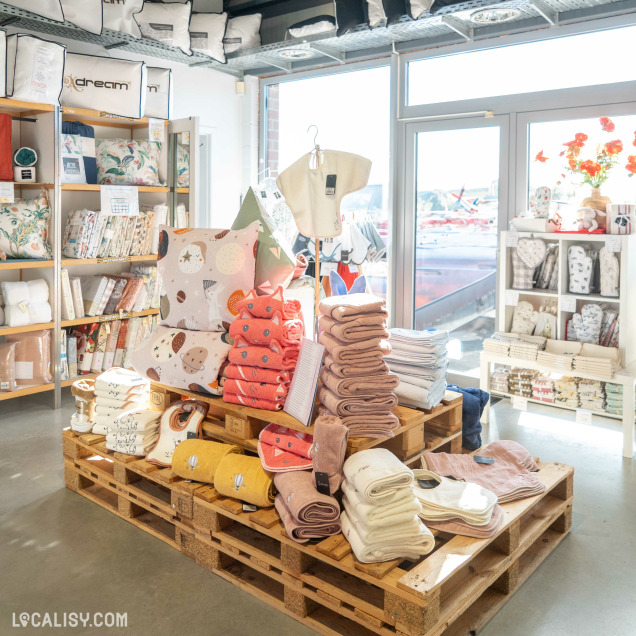 Espace lumineux de magasin avec des serviettes colorées, coussins et textiles joliment disposés sur des palettes en bois et des étagères.