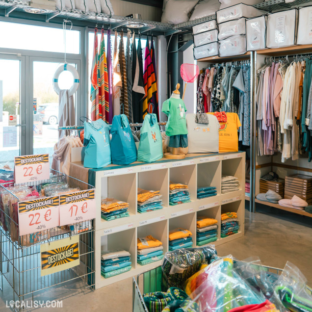 Magasin de linge et vêtements avec des étagères et portants remplis de textiles colorés, des articles en destockage et des présentations soignées par tailles et catégories.