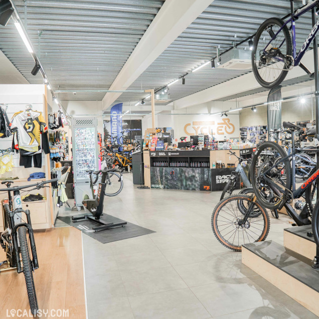 Une vue d’ensemble montre un espace rempli de vélos de ville et électriques avec un atelier en arrière-plan.