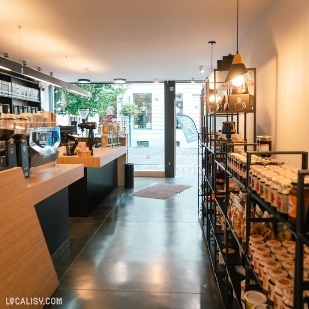 Intérieur moderne et lumineux du magasin, associant comptoir café et rayonnages gourmands.